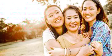 mom and two daughters smiling and hugging