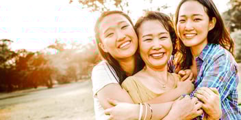 mom and two daughters smiling and hugging