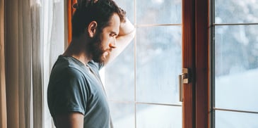 man standing in gloomy window