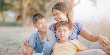 three siblings sitting together outside