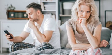 man looking at phone while woman fumes