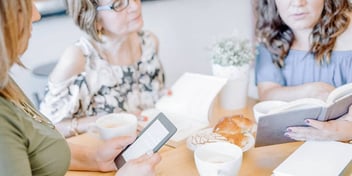 three women sitting together at table with mild friendliness
