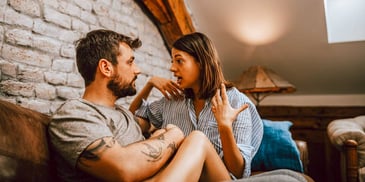 couple in intense conversation next to brick wall