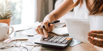 fingers pressing calculator buttons on desk
