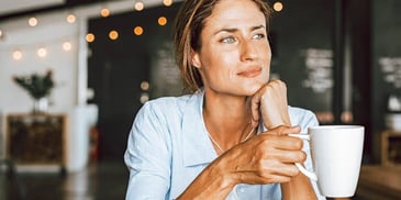 Woman thinking holding coffee mug
