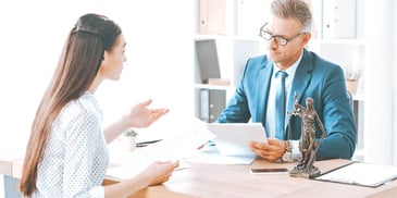 woman and man sitting at desk discussing money