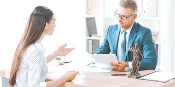 woman and man sitting at desk discussing money
