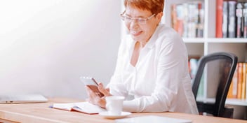 woman smiling while looking down at her phone