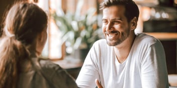 man smiling at woman both seated at table