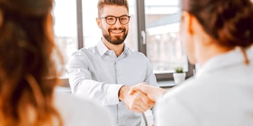 smiling man shakes hands with woman in professional setting
