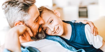 dad and son sit close on lounge chair