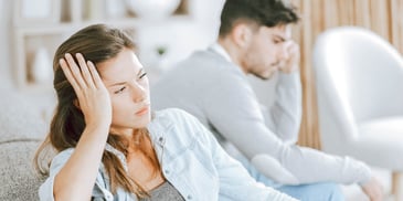 couple sitting on couch annoyed with each other