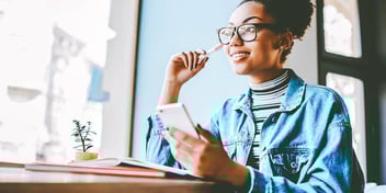 woman smiling about finances while holding phone