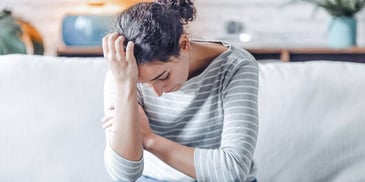 woman on couch with head in hand