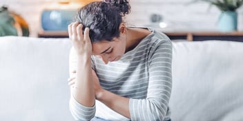 woman on couch with head in hand