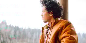 man looking out window deep in thought