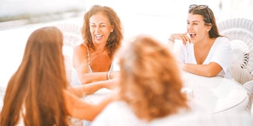 four women sitting around a table laughing