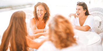 four women sitting around a table laughing