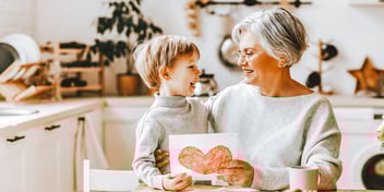 little kid hands heart drawing to smiling grandmother