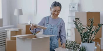 woman in overalls standing amid boxes