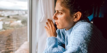 sad person looking out window at gloomy day