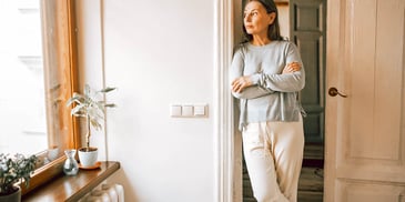 thoughtful woman standing in sunny doorway