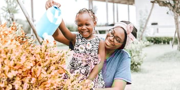mom holding smiling child in greenhouse
