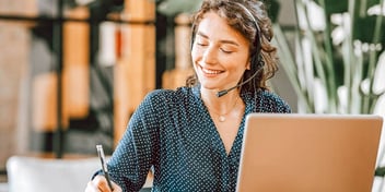 woman smiling and working on a laptop computer
