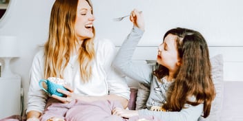 mom and daughter curled up on the couch laughing