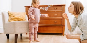 mom blowing bubbles with young child