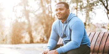 man smiling into the distance on park bench