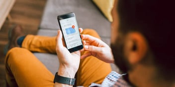 man looking at mobile phone while sitting on couch