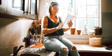 woman sits in her home smiling down at paperwork