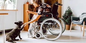 woman in wheelchair leaning down to pet dog