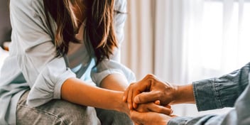people clasping hands in grief