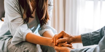 people clasping hands in grief