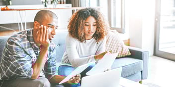 young people seated on couch examine paperwork 