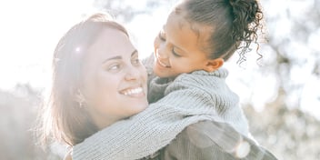 smiling mom carrying daughter on shoulders