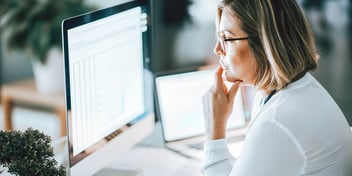 woman tapping chin in front of computer screen