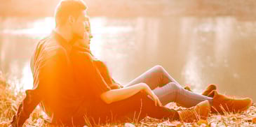 seated couple on riverbank staring at water