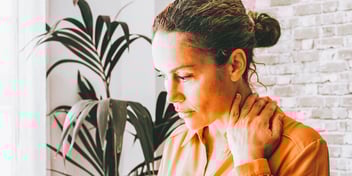 woman deep in thought next to large palm plant