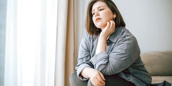 thoughtful woman sitting by window
