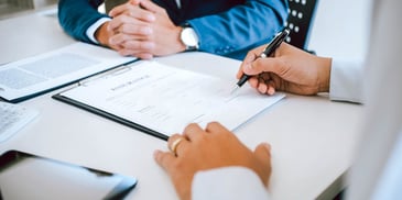 hands signing important papers on desk
