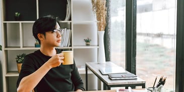 Asian man drinking tea and looking out the window