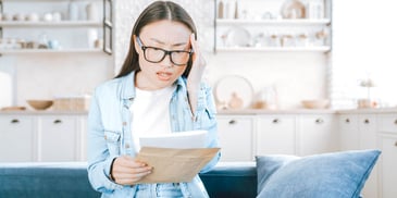 woman holding paperwork looking shocked and upset