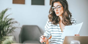 woman with pen and paper in hand working