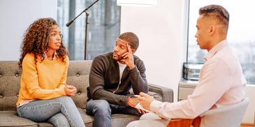 couple sitting in a room with a mediator or therapist
