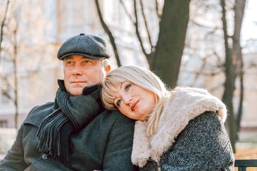 dreamy woman resting head on man's shoulder in a winter park