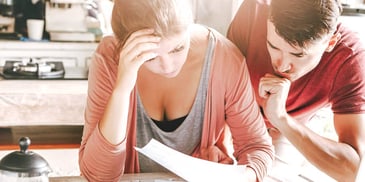 couple sitting close together in their kitchen looking at paperwork