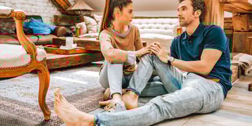 couple sitting on the floor holding hands and having a difficult conversation